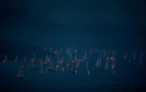 Articles & Case Studies 5 Green boat in an ocean surrounded by red boats.