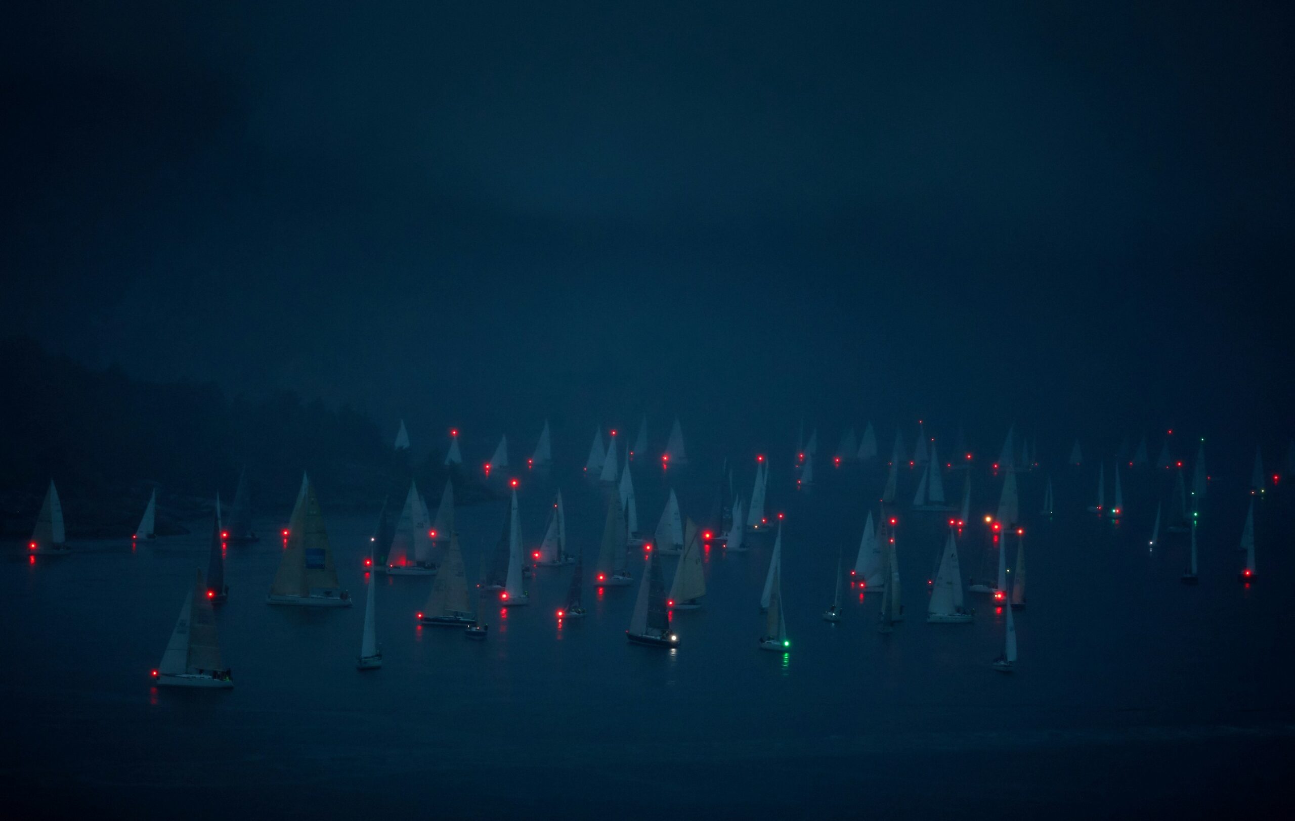 Green boat in an ocean surrounded by red boats.