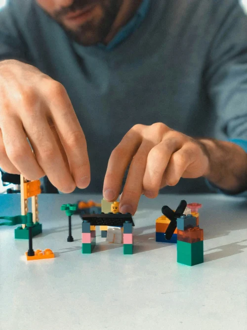 Man building with colorful LEGO blocks at table